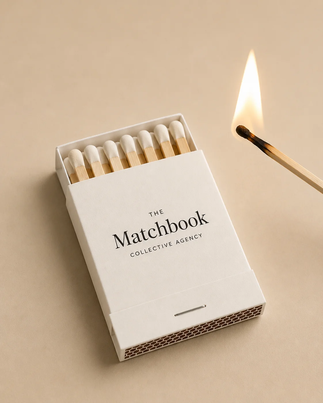The Matchbook Collective Agency matchbook beside a lit match on warm ivory paper.